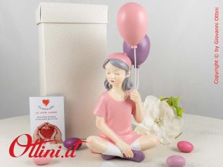 D6823 - La Ragazza seduta con Palloncini di Cuorematto è una bomboniera solidale per ragazze e bambine completa di confezione.